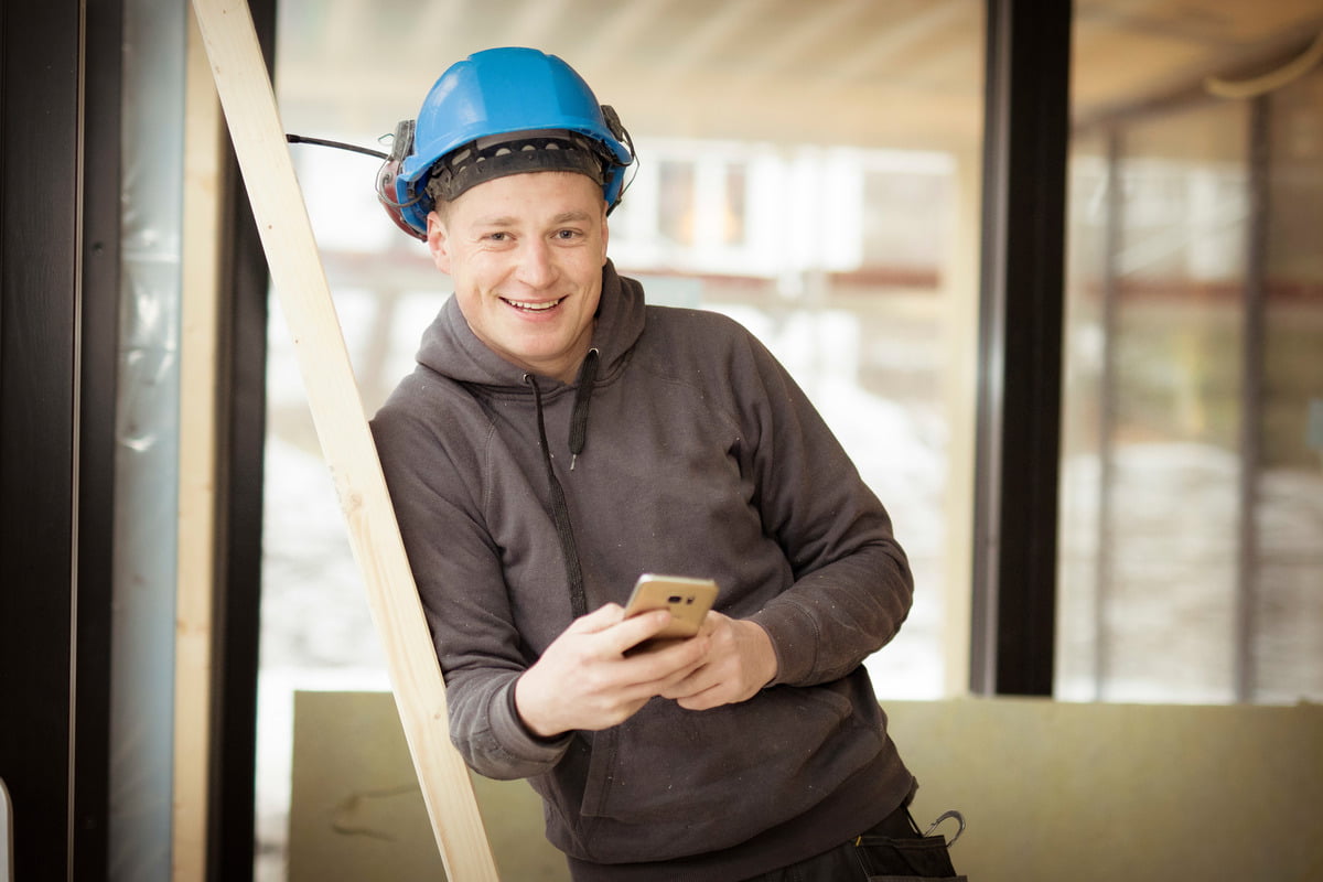Snekker med hjelm og telefon i hånden