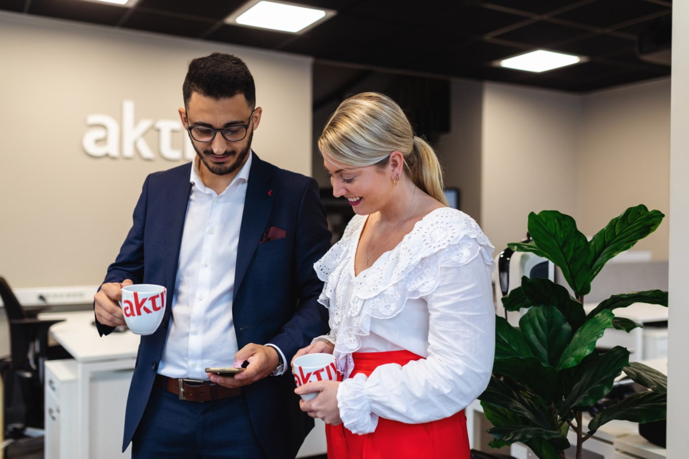 Dame og mann fra Aktiv Eiendom sjekker mobilen