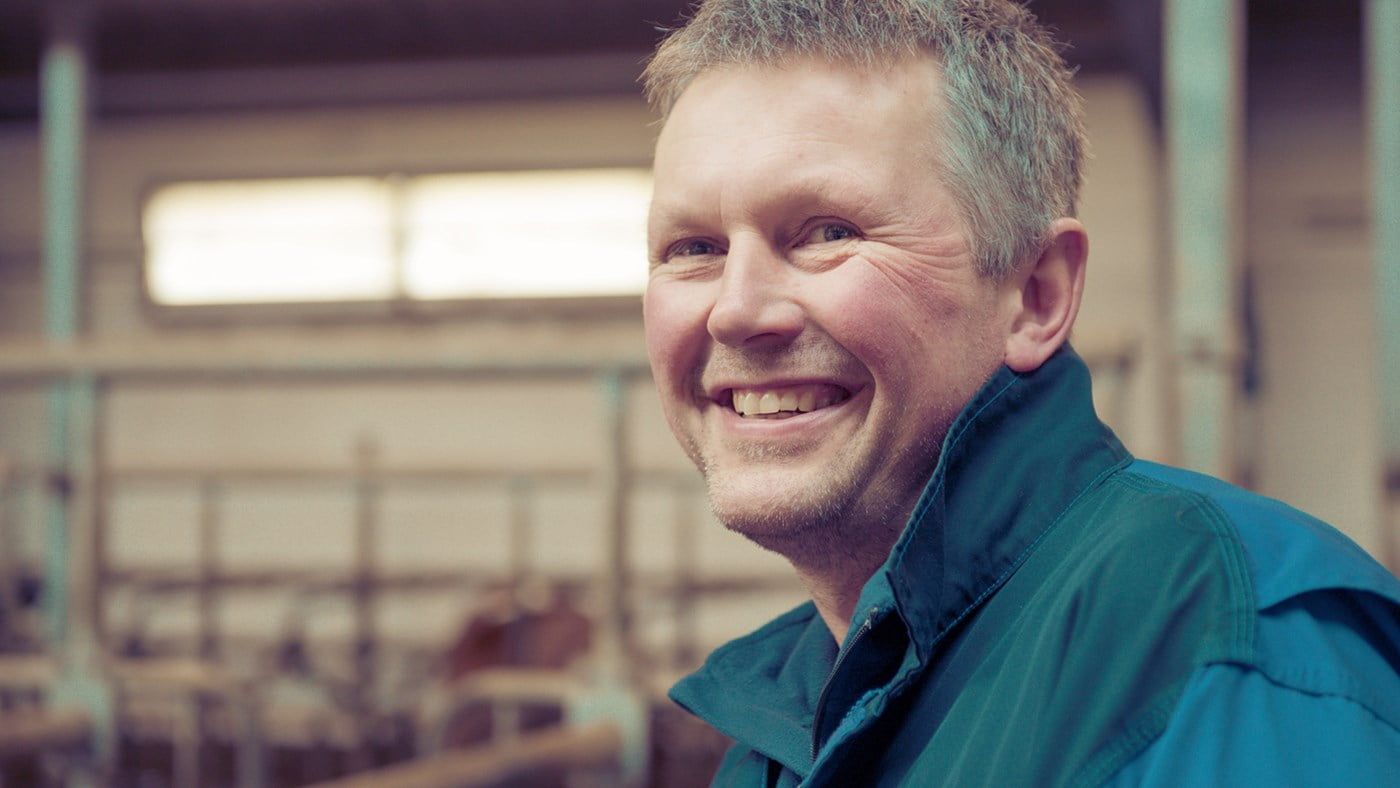 Smilende mannlig bonde i fjøset.